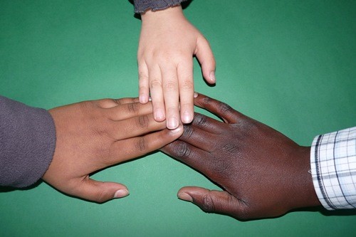 3 Hände unterschiedlicher Hautfarbe berühren sich