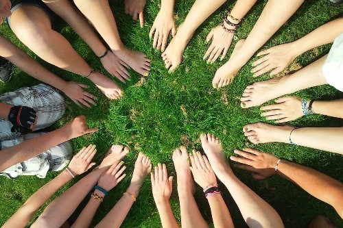 Hände und Füße formen eine Kreis auf einer grünen Wiese